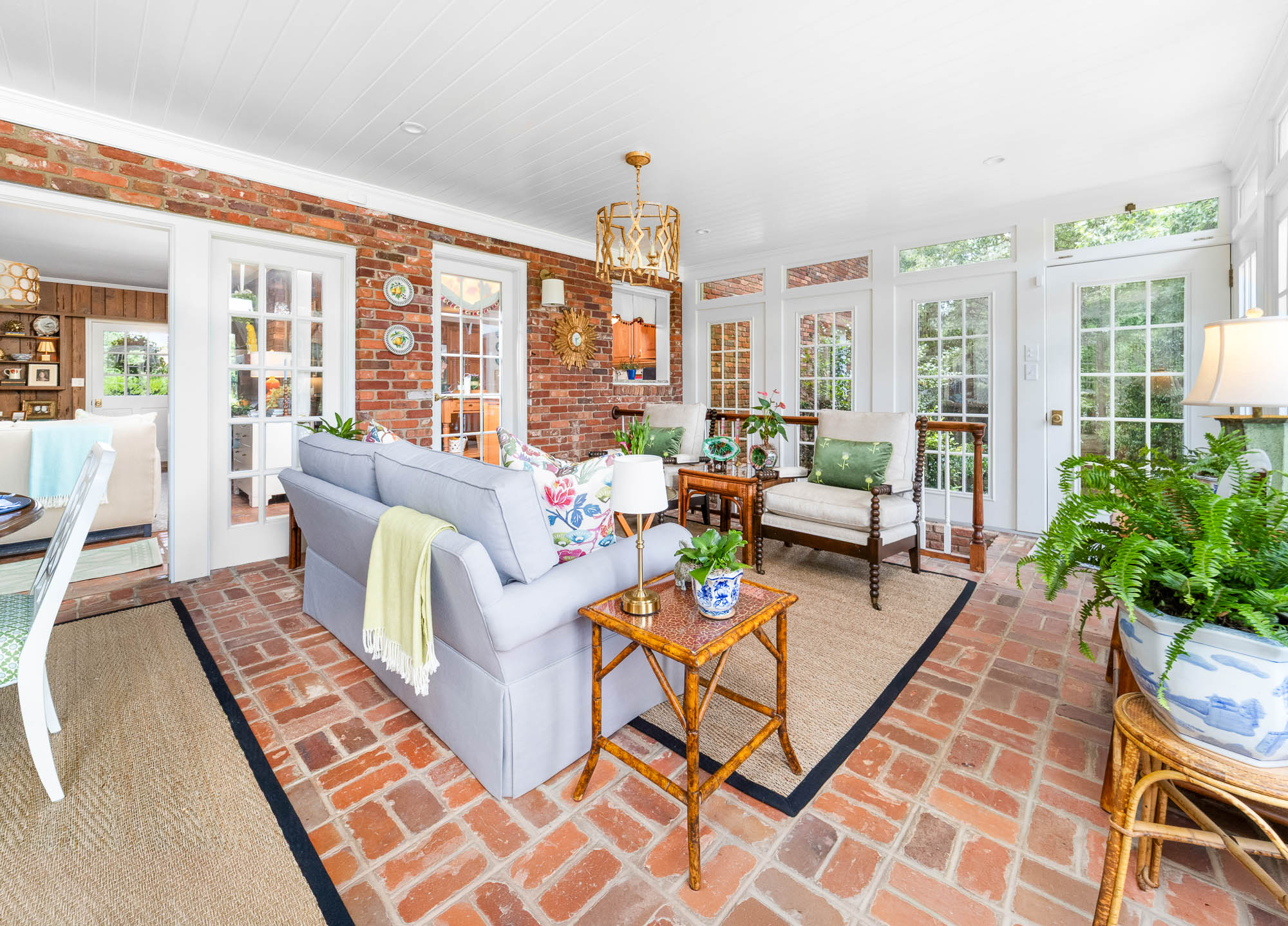 Bright brick-floored sunroom with French doors and garden views
